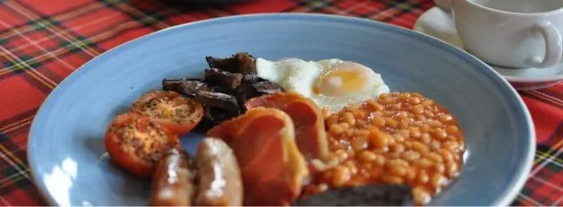 Desayuno tradicional escocés: salchichas, tomate, huevo y alubias