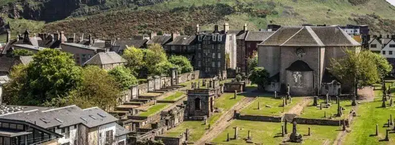 canongate-kirk-salisbury-crags-edimburgo-escocia Vista del Cementerio de Canongate y Salisbury Crags en Holyrood Park en Edimburgo, Escocia